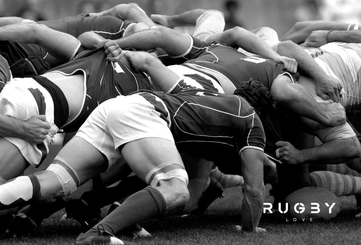 Black and white photo of rugby players in a scrum, with rugby Love logo in the lower right hand corner